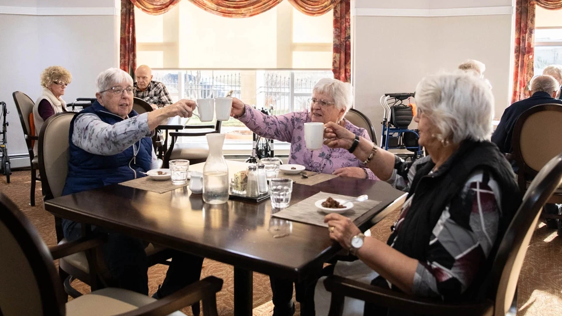 A group of older people sitting at a table in a dining room.